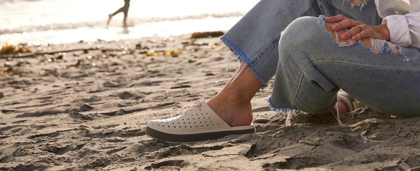 woman sitting on the beach with joybees weekend mule shoe on 