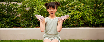 little girl holding joybees skate shoes on her hands and making a funny face