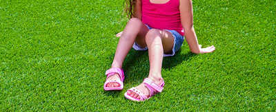 little girl sitting in grass with joybees adventure sandals on