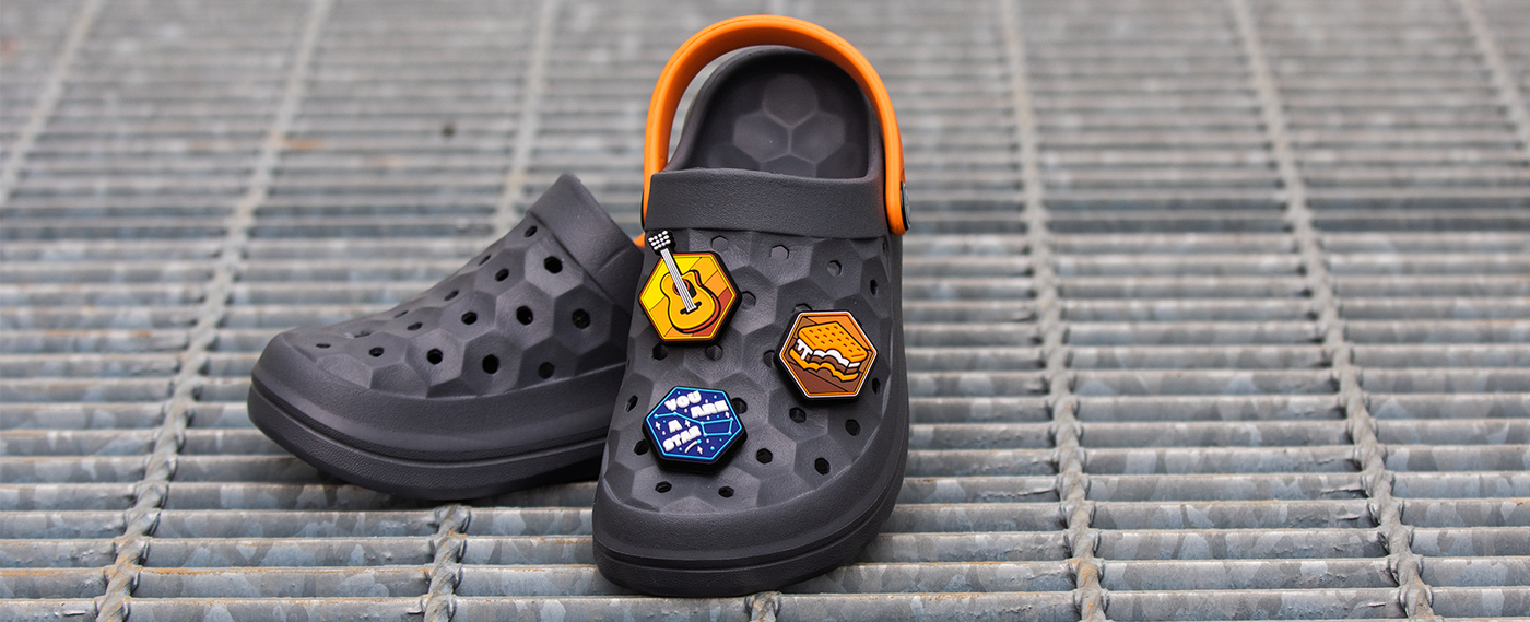 joybees clogs on a metal grid with camping themed popinz shoe charms