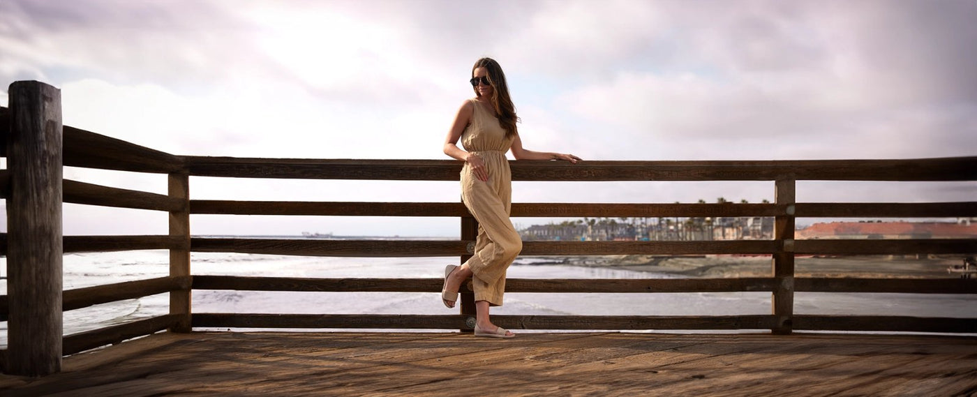 woman standing on wooden pier over ocean with Joybees Flats on
